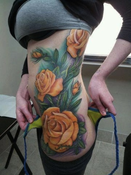 Yellow Rose Flower With Green Leaves Tattoo On Side Rib