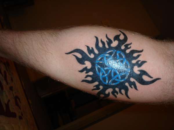 Black Tribal And Blue Celtic Sun Tattoo On Back Leg