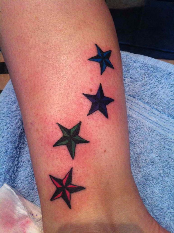 Blue, Green And Pink Nautical Star Tattoos On Leg