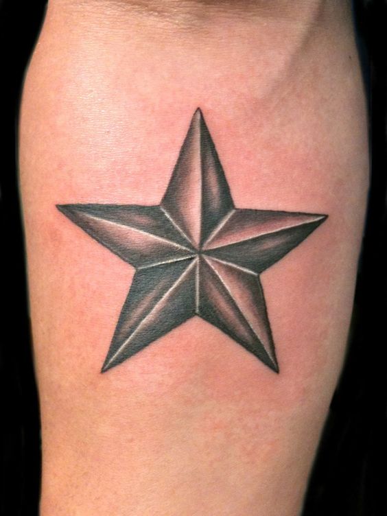 Tatuaje de una estrella náutica gris y negra en el antebrazo