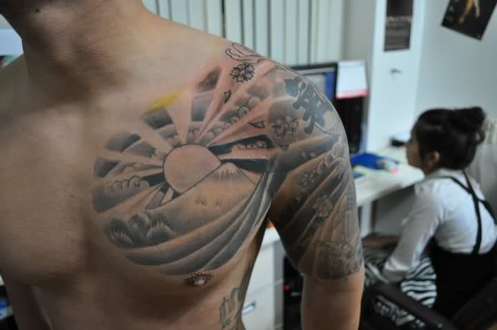 Grey Ink Rising Sun Tattoo On Man Front Shoulder