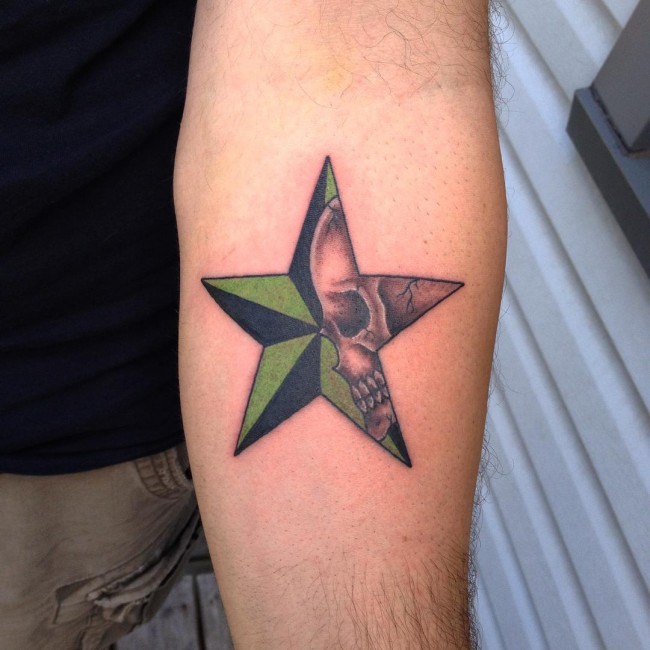 Tatuaje de una calavera gris con una estrella náutica en el antebrazo izquierdo