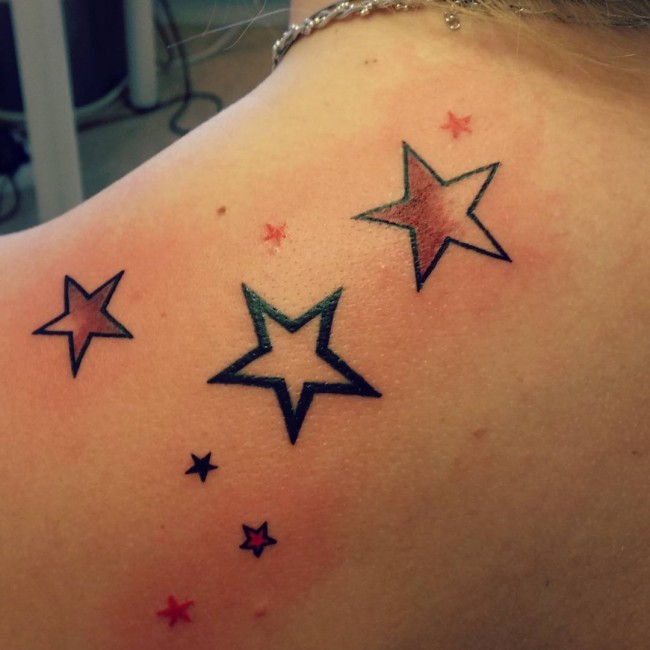 Tatuajes de estrellas pequeñas y de colores en el hombro trasero izquierdo