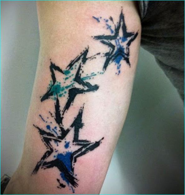 Tatuajes de estrellas de acuarela en el interior del bíceps