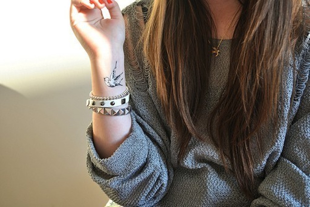 Mädchen mit Taube Tattoo am Handgelenk