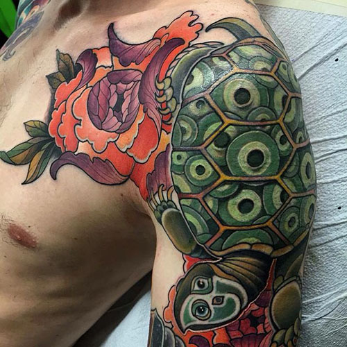 Green And Orange Ink Turtle Tattoo On Man Left Shoulder