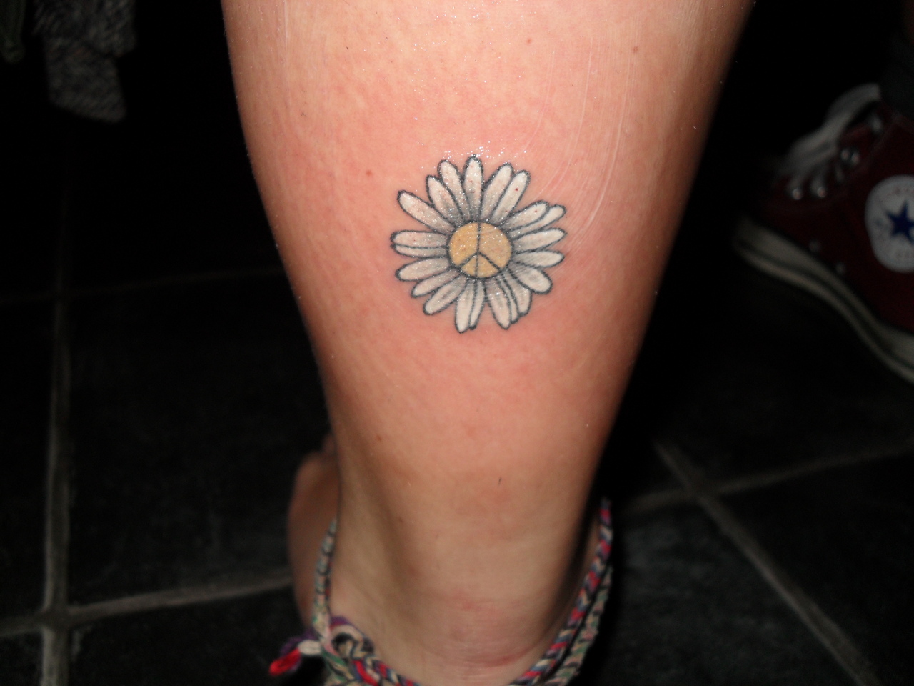 Peaqce Symbol In Daisy Flower Tattoo On Back Leg