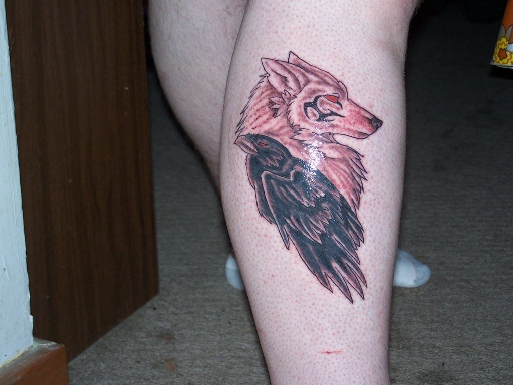 Red Eyes Wolf Head And Raven Tattoo On Side Leg