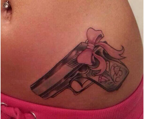 Pistol With Pink Bow Tattoo On Hip
