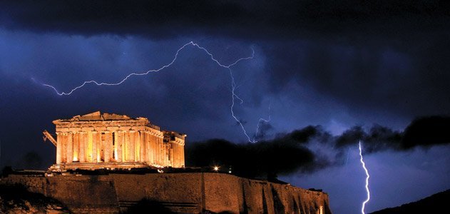 The Parthenon Temple Lit Up At Night With Lightening In Background