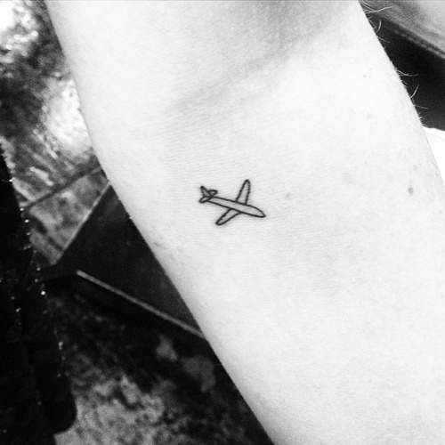 A Small Black Outline Airplane Travel Tattoo
