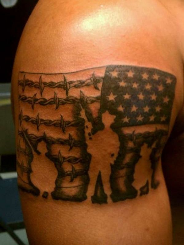 Black Ink Usa Flag With Barbed Wire And Soldier Tattoo On Bicep.