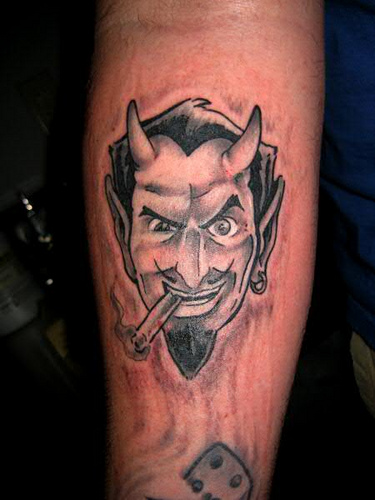 Black & Grey Smoking Devil Face Tattoo On Forearm
