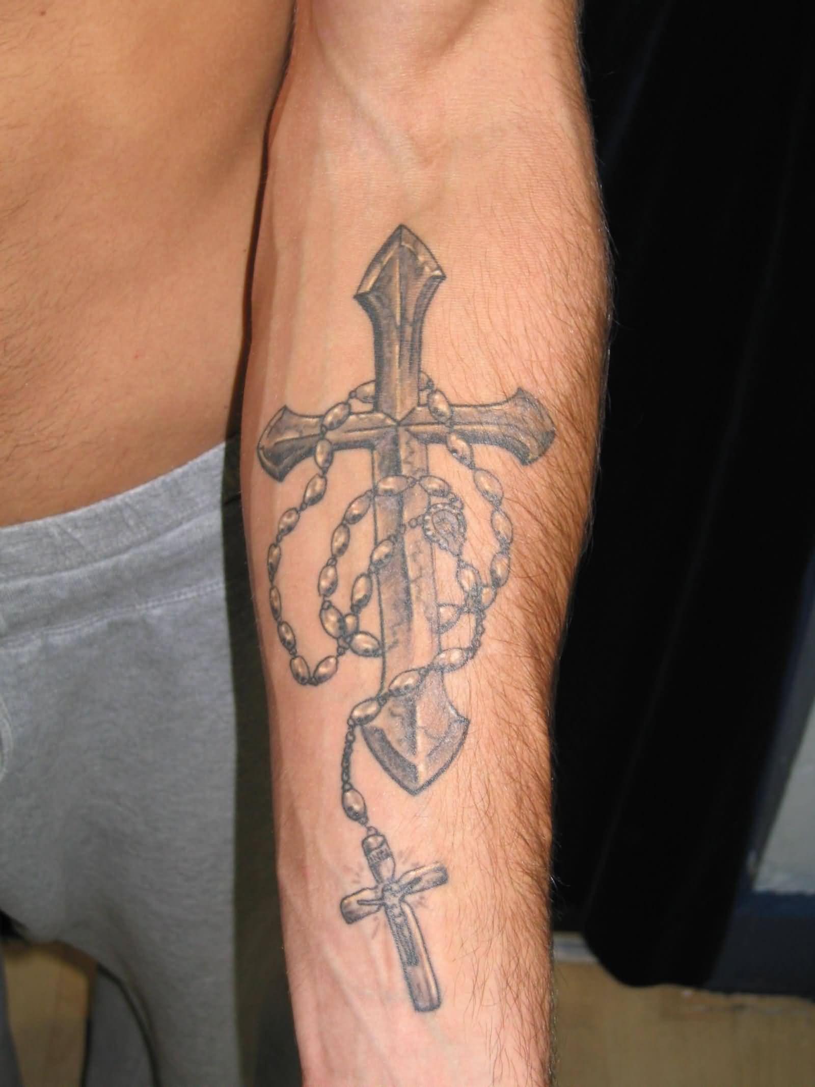 Grey Ink Holy Rosary And Cross Tattoo On Forearm