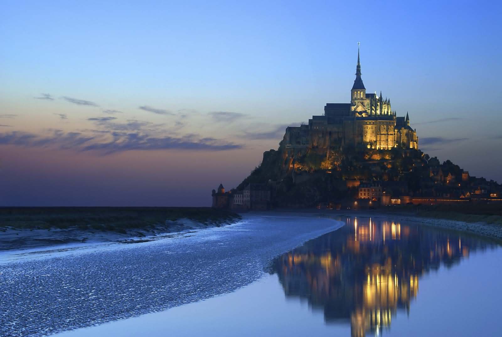 Water reflection of Mont Saint-Michel during low tide at dusk