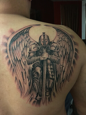 Black & Grey Ink Guardian Angel With Sword Tattoo On Back Shoulder