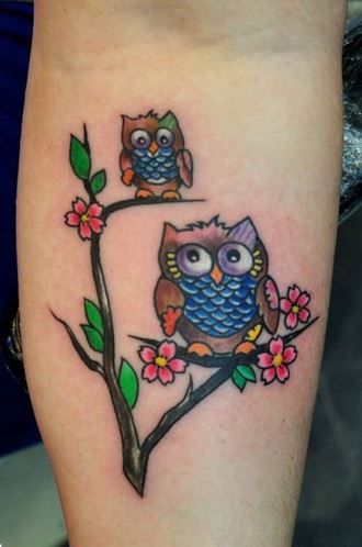 Wonderful Colored Mother & Baby Owl Sitting On Floral Branches Tattoo On Forearm