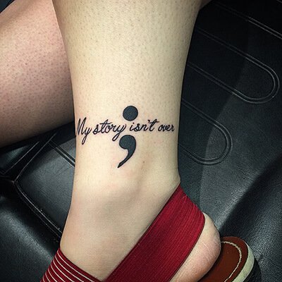 Beautiful Black Ink Wording ‘My Story Isn’t Over’ With Semicolon Tattoo On Ankle For Girls
