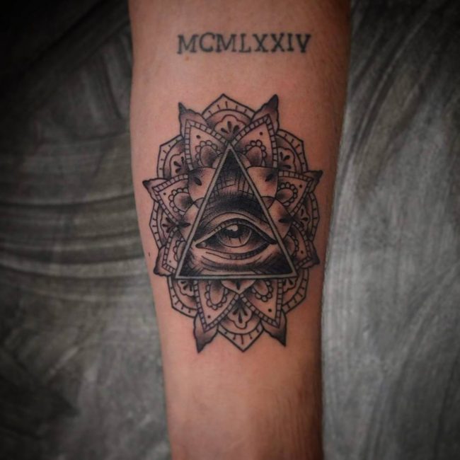 Black Ink Mandala Flower & Illuminati Tattoo On Forearm