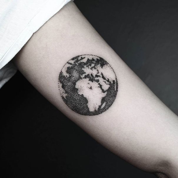 Black and white dotted shaded earth tattoo on upper sleeve