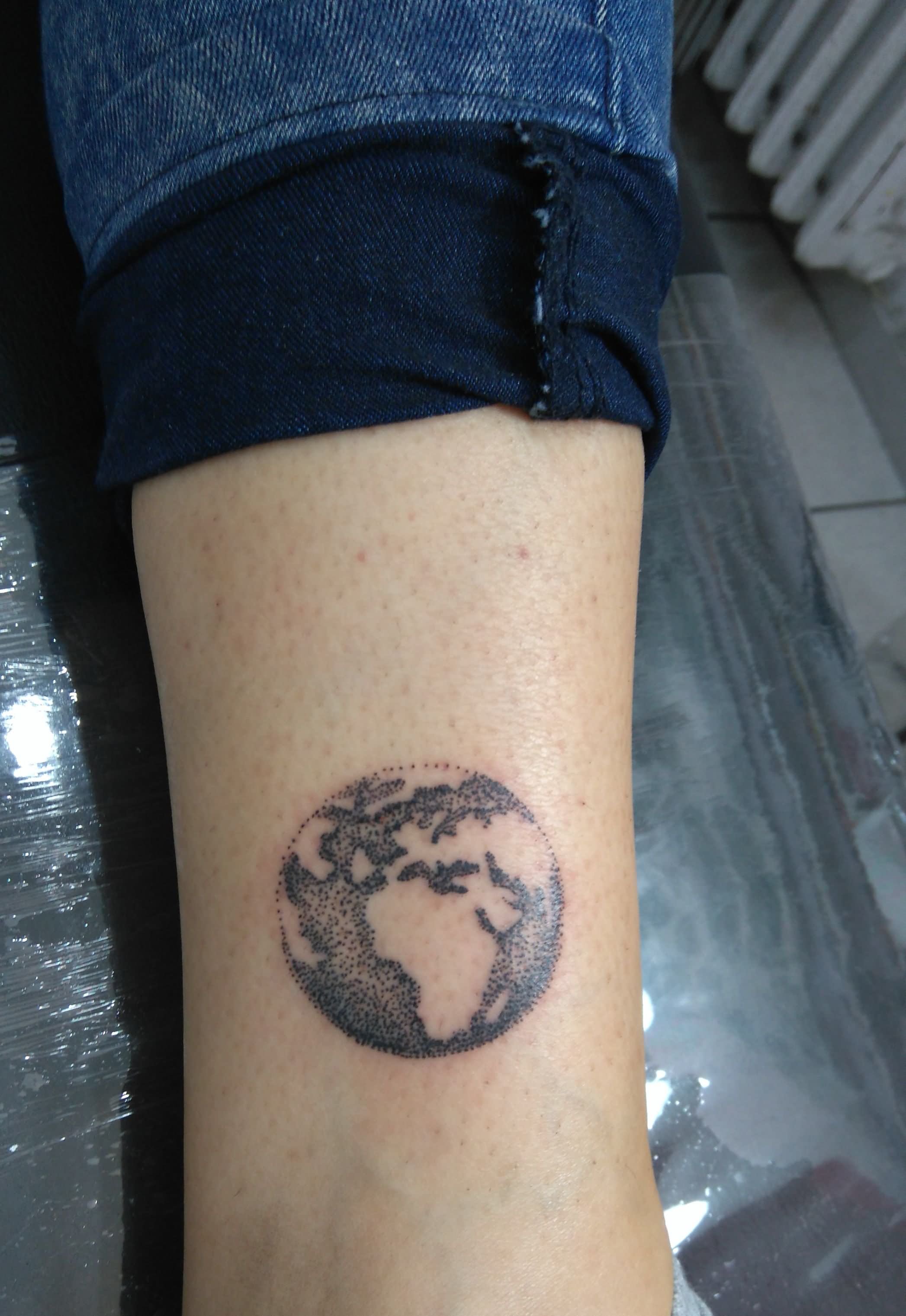 Black and white shaded earth tattoo on inner arm