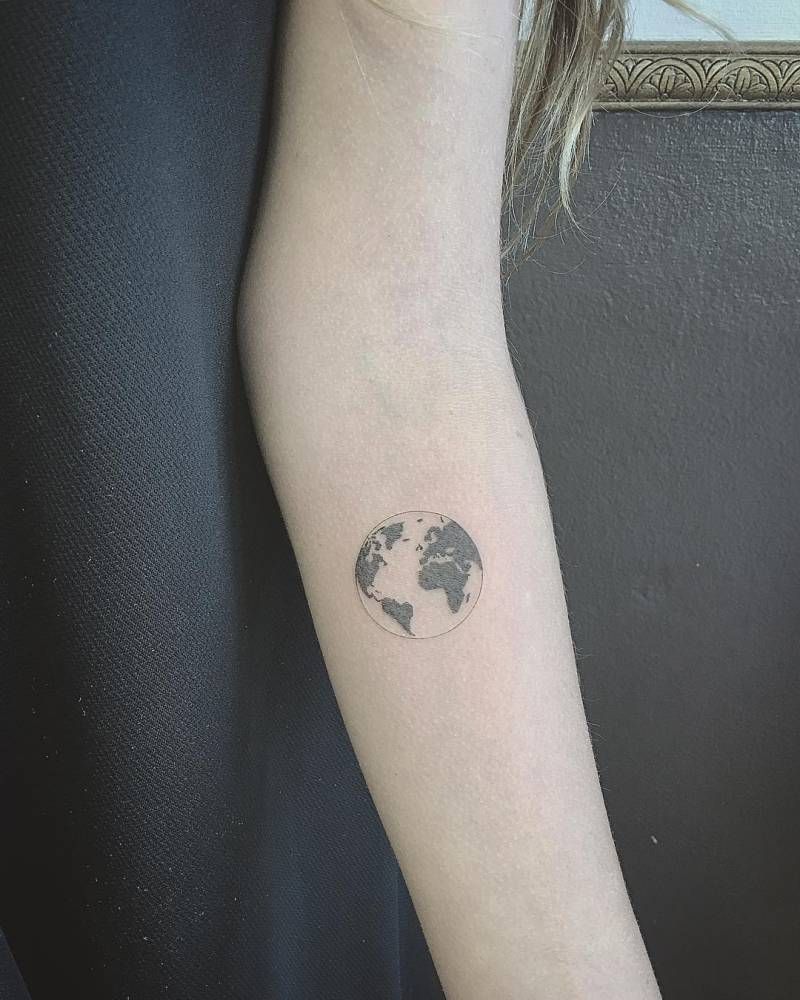 Black and white shaded earth tattoo on inner forearm