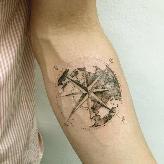 Black and white shaded earth tattoo with compass on inner arm