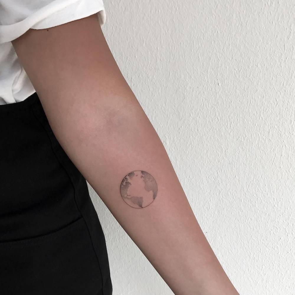 Black and white small shaded earth tattoo on inner arm