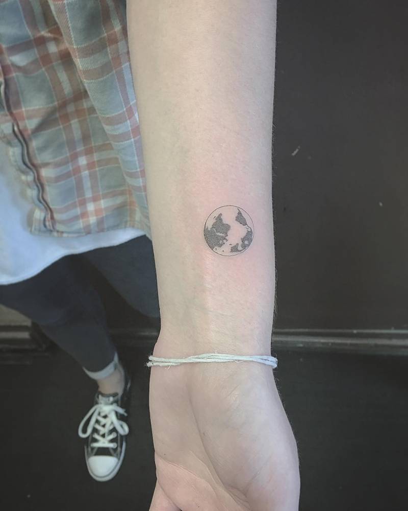 Black and white small shaded earth tattoo on inner forearm