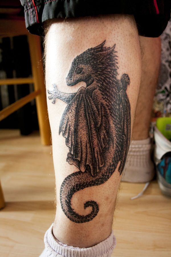 Black baby dragon tattoo on right lower leg