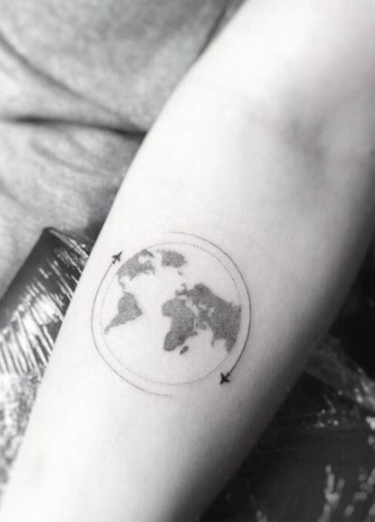 Black globe and airplanes tattoo on inner arm