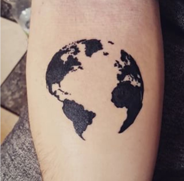 Black map outline on globe tattoo on arm