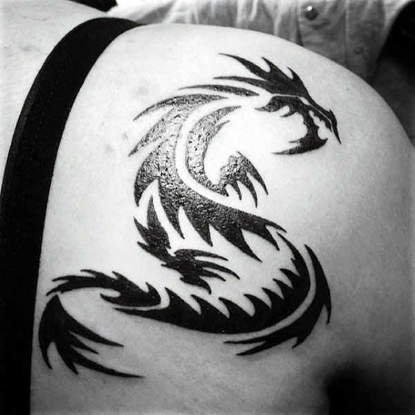Black small tribal dragon tattoo on upper right shoulder