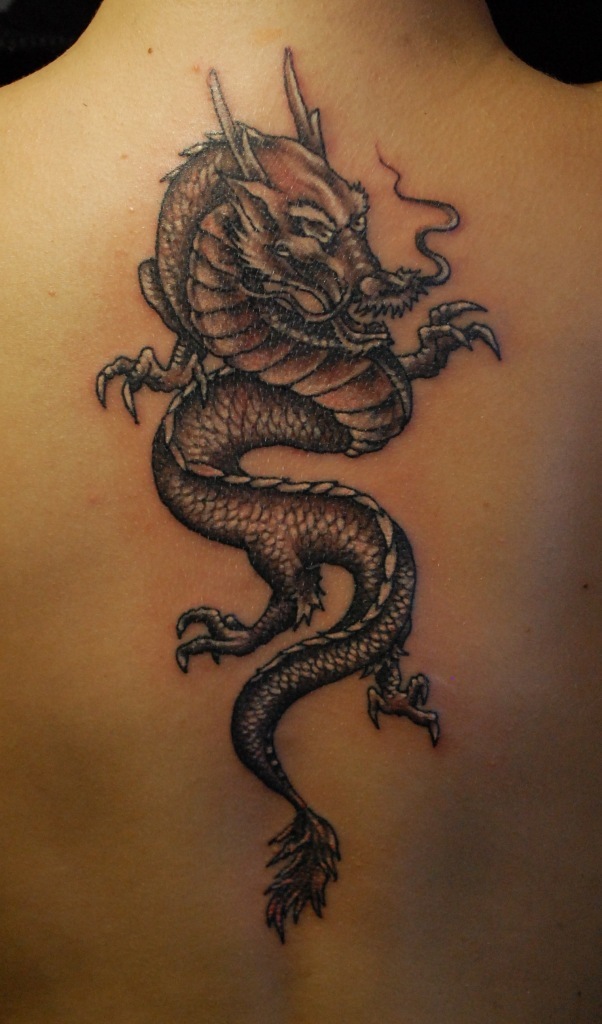 Black spiral Japanese dragon tattoo on woman upper back
