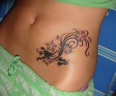 Black tribal dragon and colored flower tattoo on left navel for women