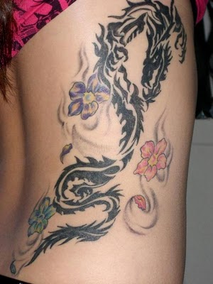 Black tribal dragon and colourful flowers tattoo on lower right back for women