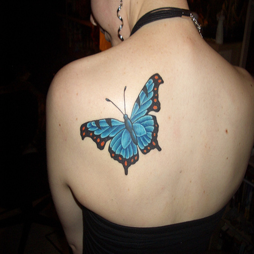 Blue butterfly tattoo on girls left upper-back shoulder