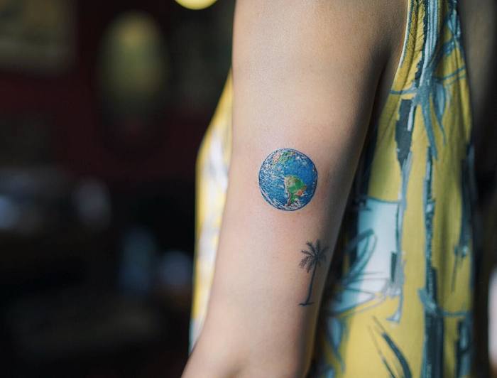 Colored 3d earth tattoo with palm tree on inner arm