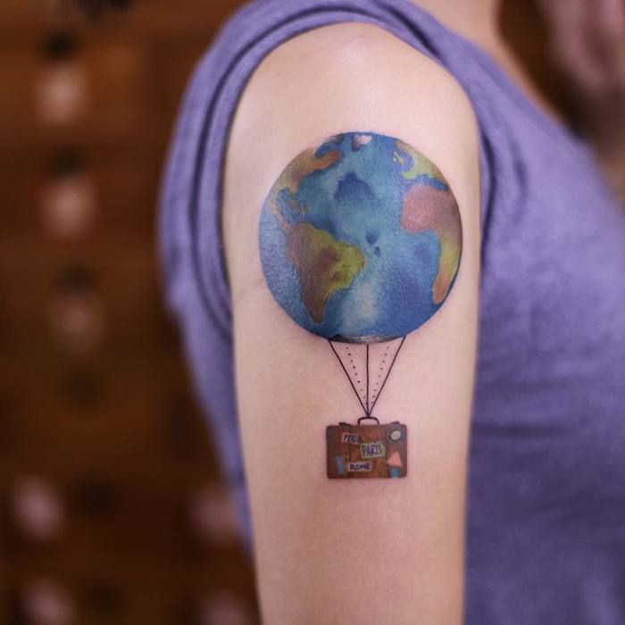 Colored earth balloon tattoo on upper arm for women