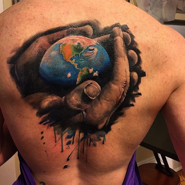 Colored hand holding earth tattoo on back for men