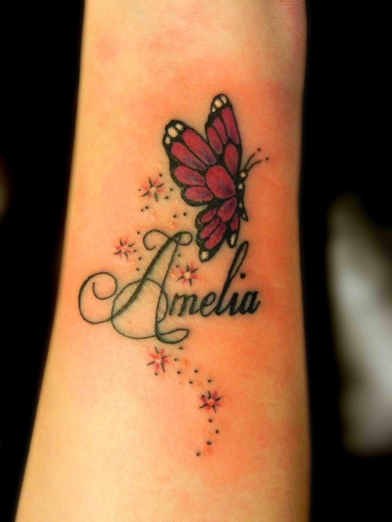 Colorful butterfly with name tattoo on wrist
