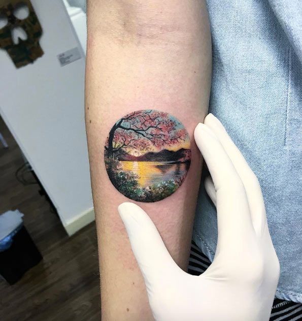 Colorful earth with scenery tattoo on inner forearm