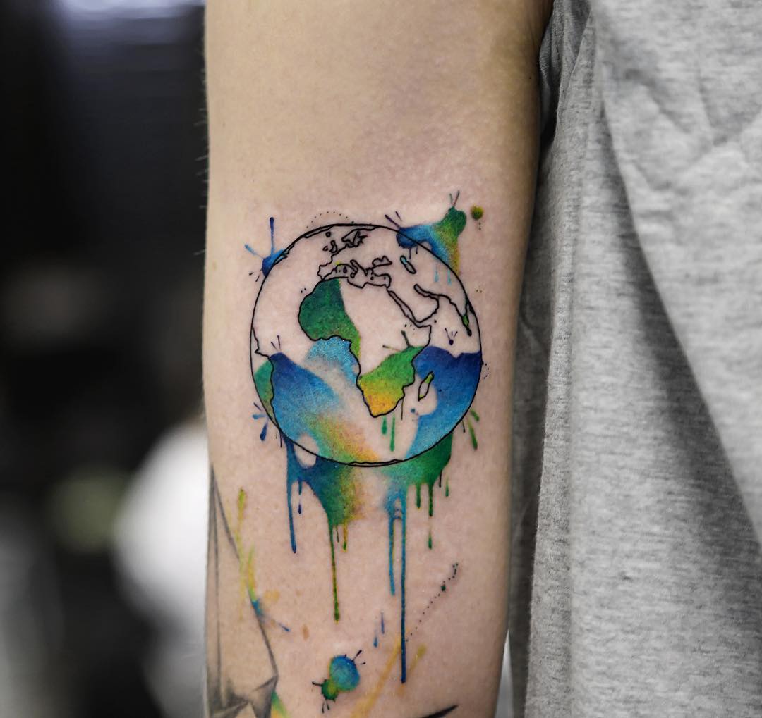Colorful water-colored black outlined earth tattoo on inner arm