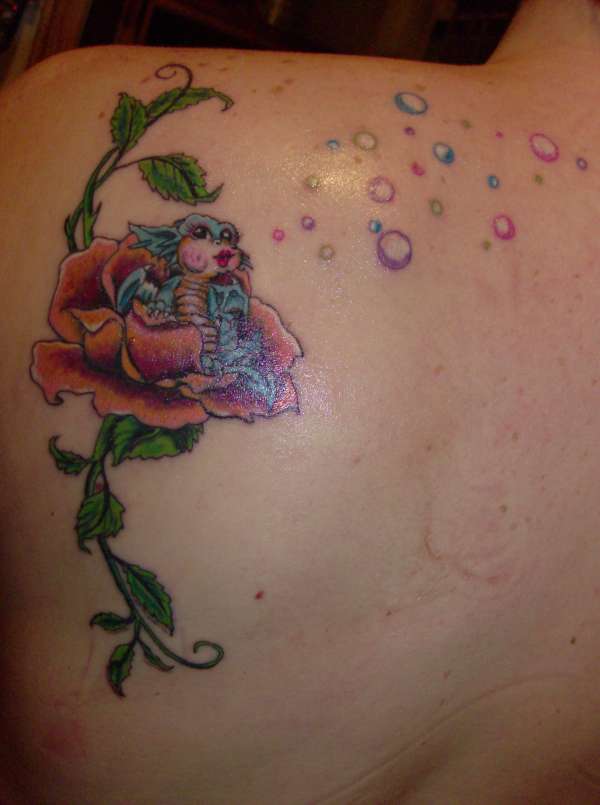 Colored baby dragon tattoo with flower on upper left back