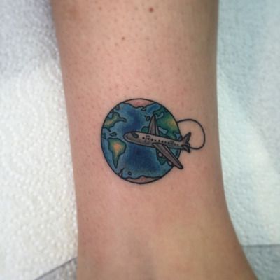 Colorful globe and airplane tattoo on inner arm