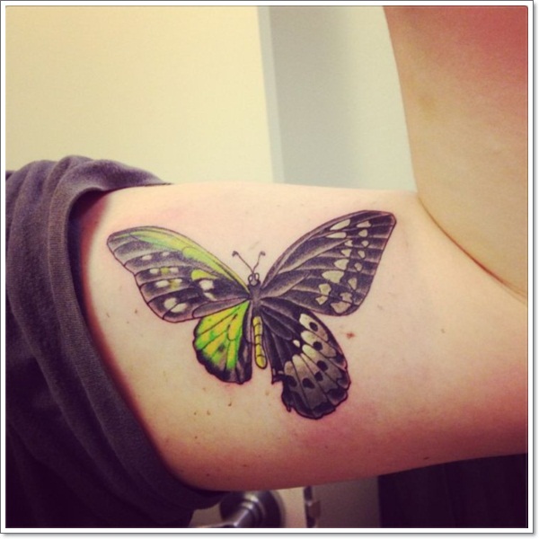 Green and black butterfly tattoo design on biceps