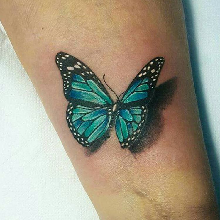 Green butterfly tattoo on inner arm