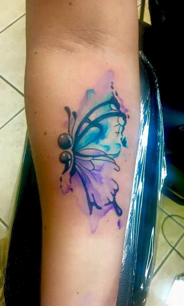 Half Watercolor butterfly tattoo on middle inner arm