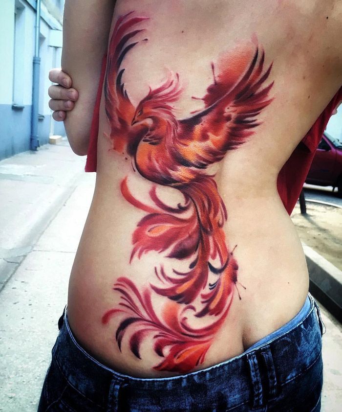 Multicolored rising phoenix tattoo on girl side back