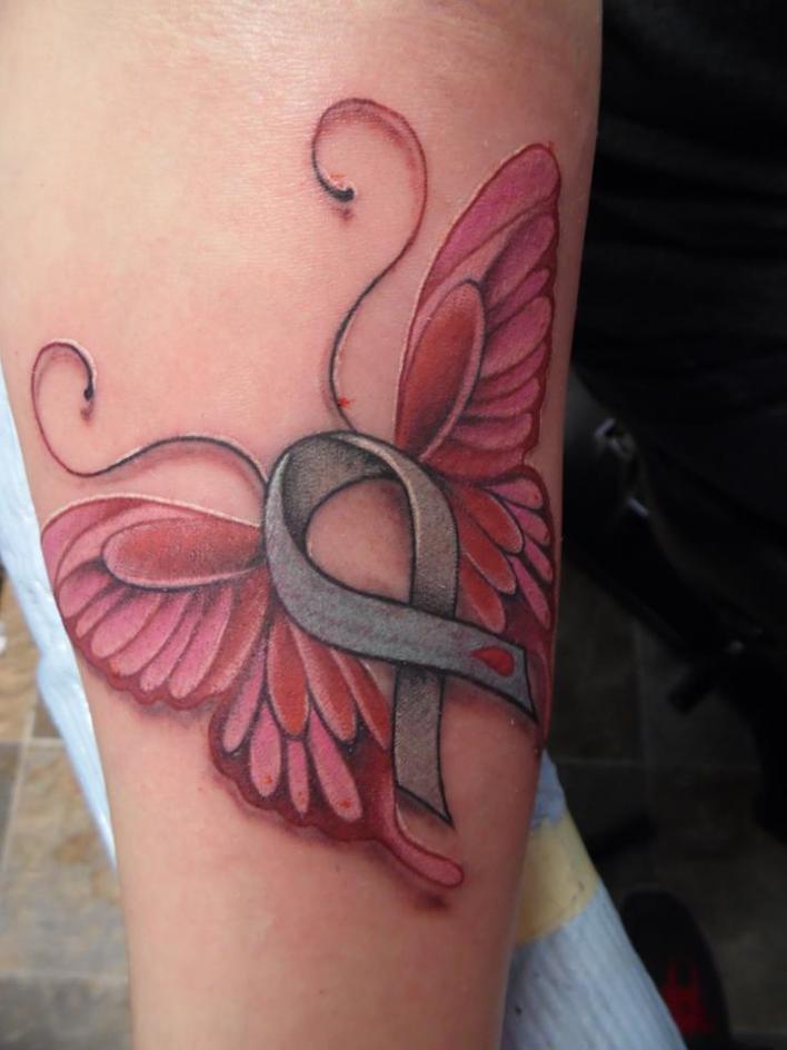 Pink cancer ribbon butterfly tattoo on inner arm
